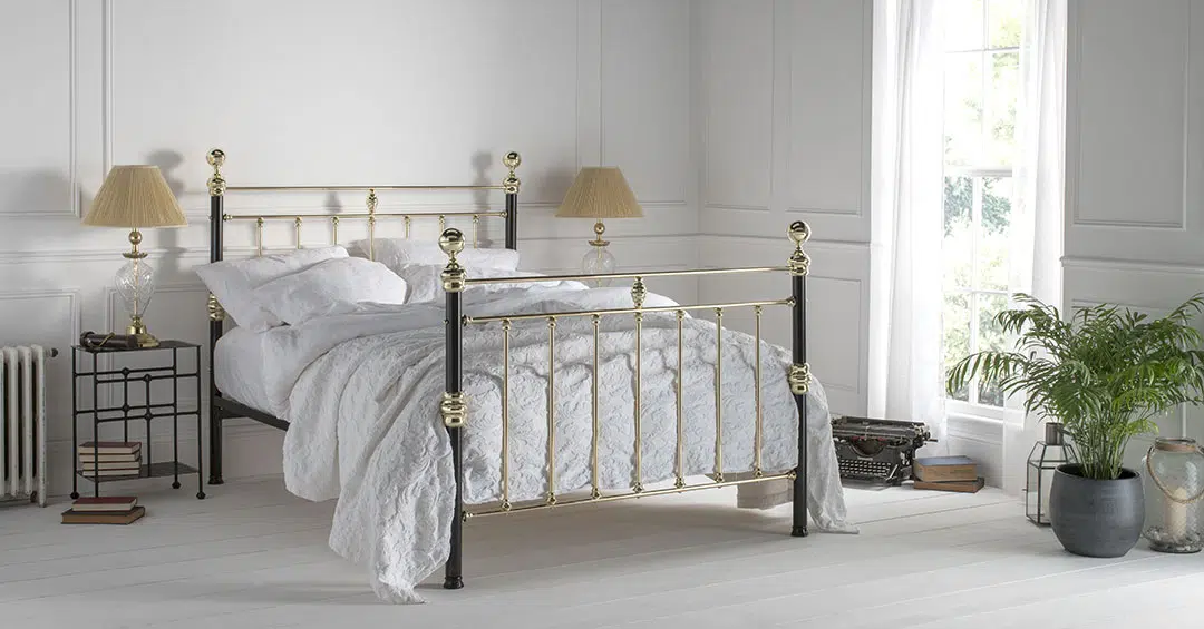 George bed with polished brass detailing and black iron posts in a classic white bedroom