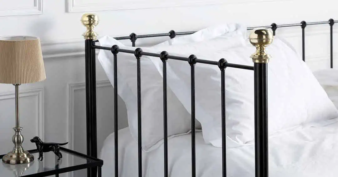 Linear metal detailing of the Garce black day bed with decorative knops and crisp white pillows