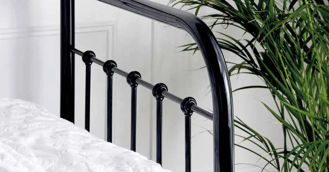 Edward day bed headboard showing black rail detailing and polished nickel arch with leafy plant in background