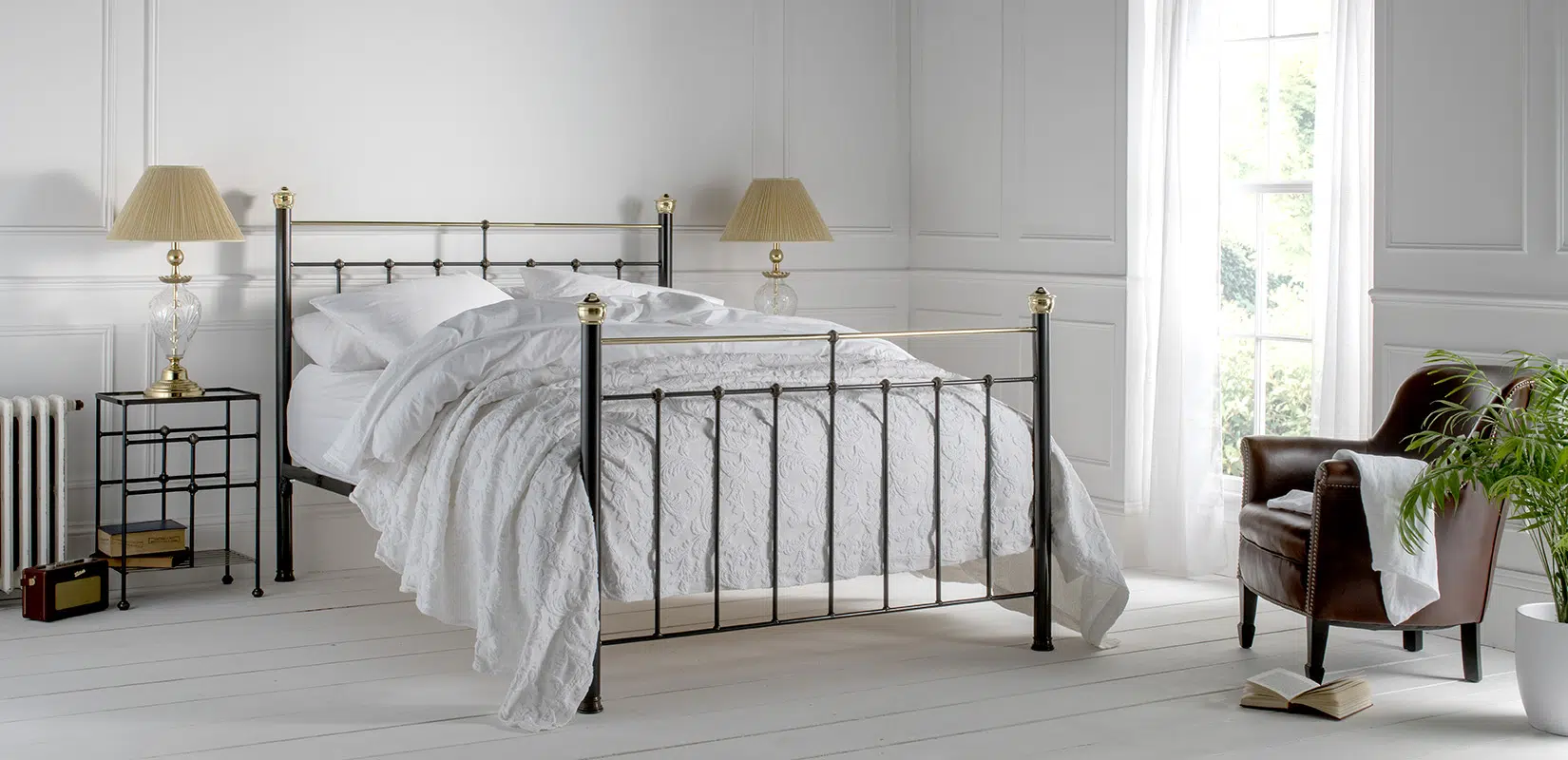 Beatrice black iron bed with brass finials and white bedding in a classic bedroom interior