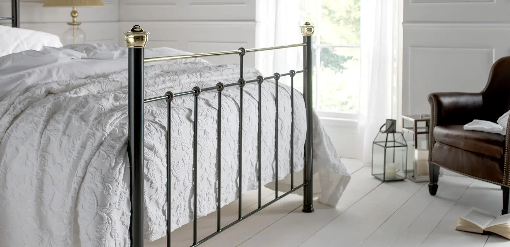 Side view of Beatrice bed showing slim black iron bars and contrasting brass detailing