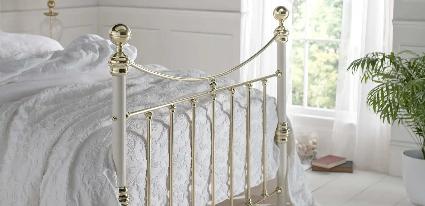 Elizabeth bed with classic brass vertical rods and sculpted finial ends, styled with white bedding