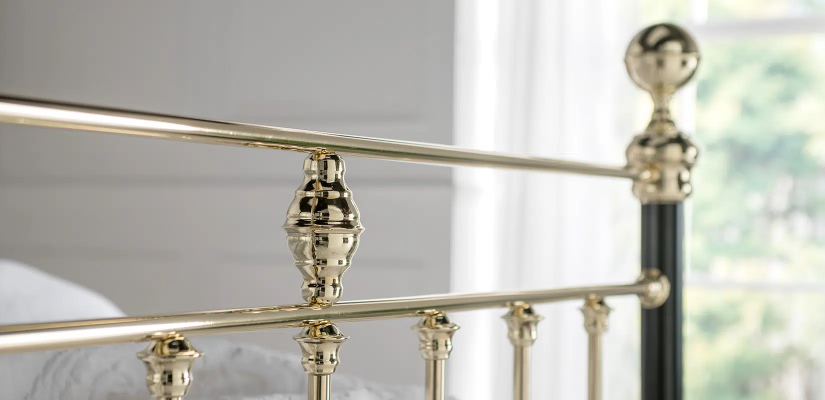 Detailed view of George bed’s ornate polished brass finial and top rail