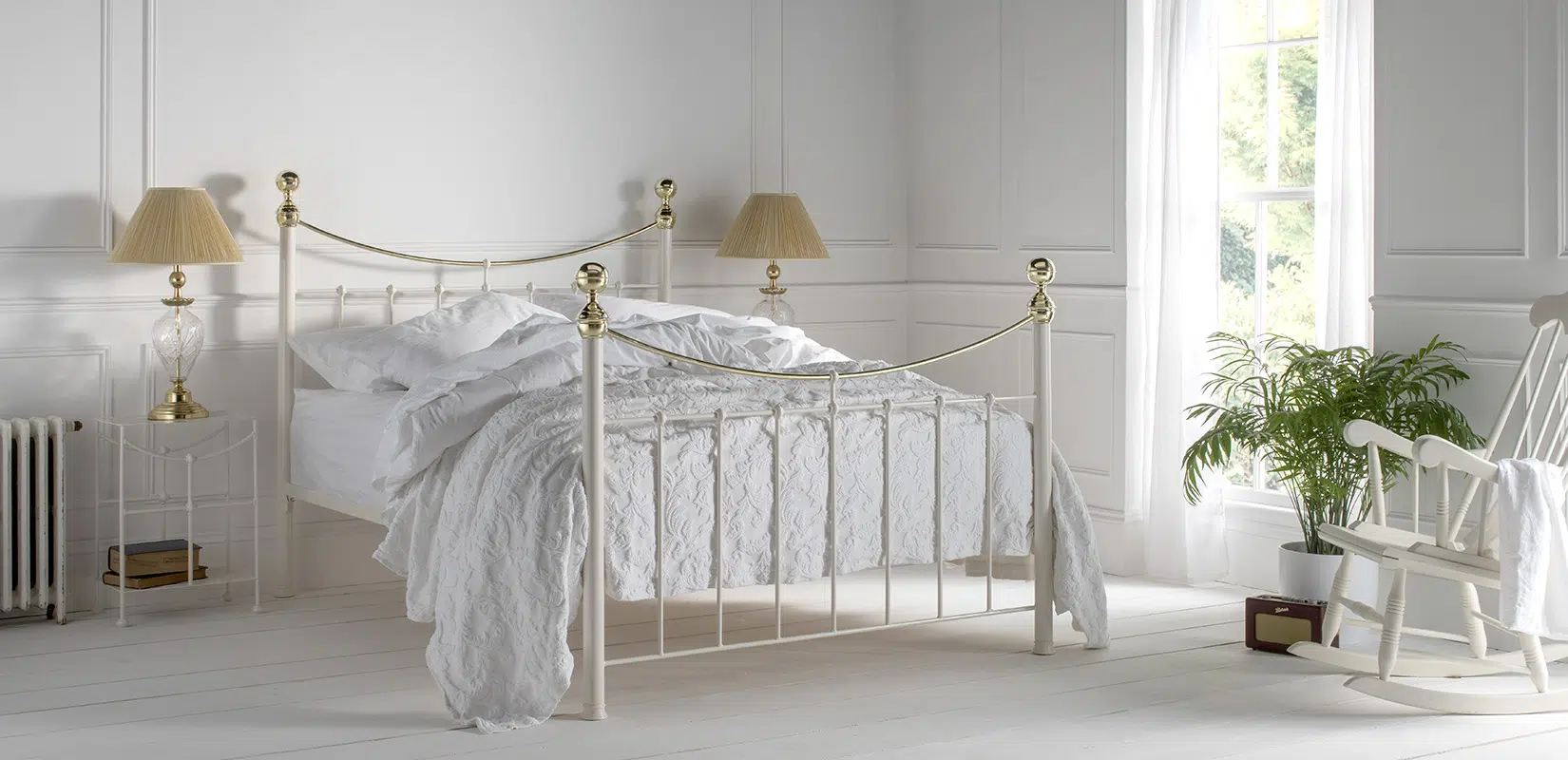 Victoria brass bed with tall corner posts and decorative finials in a bright classic bedroom