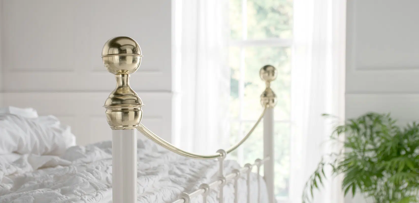 Detailed close-up of Victoria brass bed finial and gently arched top rail in polished finish