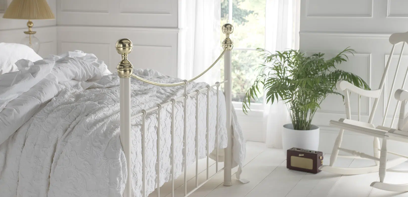 Side view of Victoria brass bed featuring smooth curved headboard and bright natural lighting
