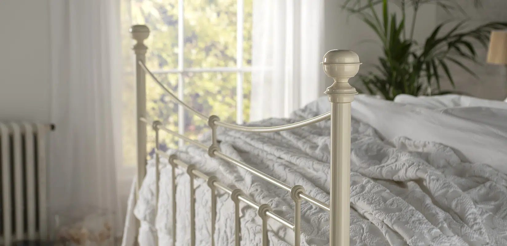 Detailed view of Lily bed's decorative brass finial and top rail with soft natural lighting through large windows