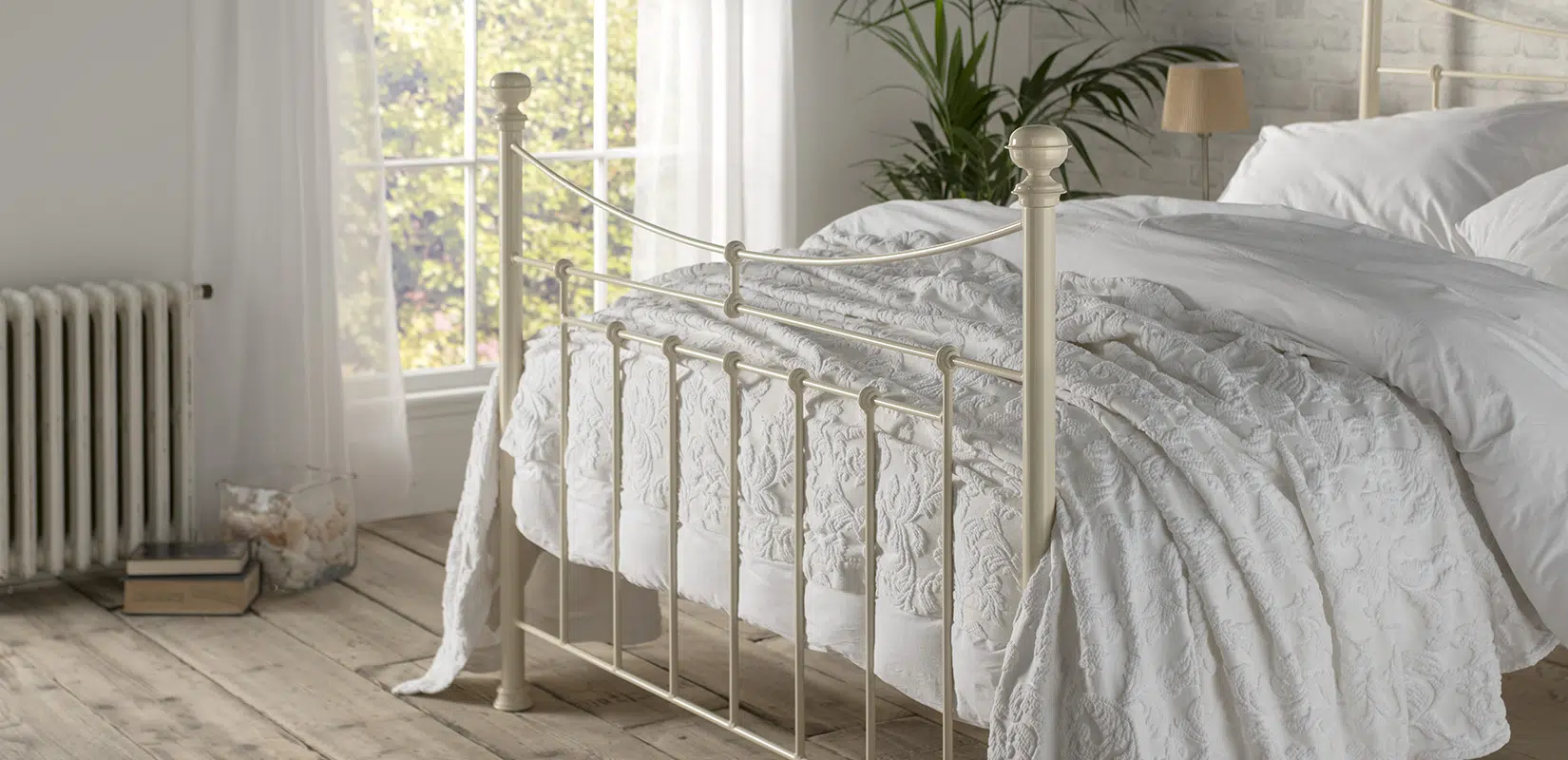 Close-up side view of the Lily iron bed with vertical bar detailing and elegant frame design in a sunlit room