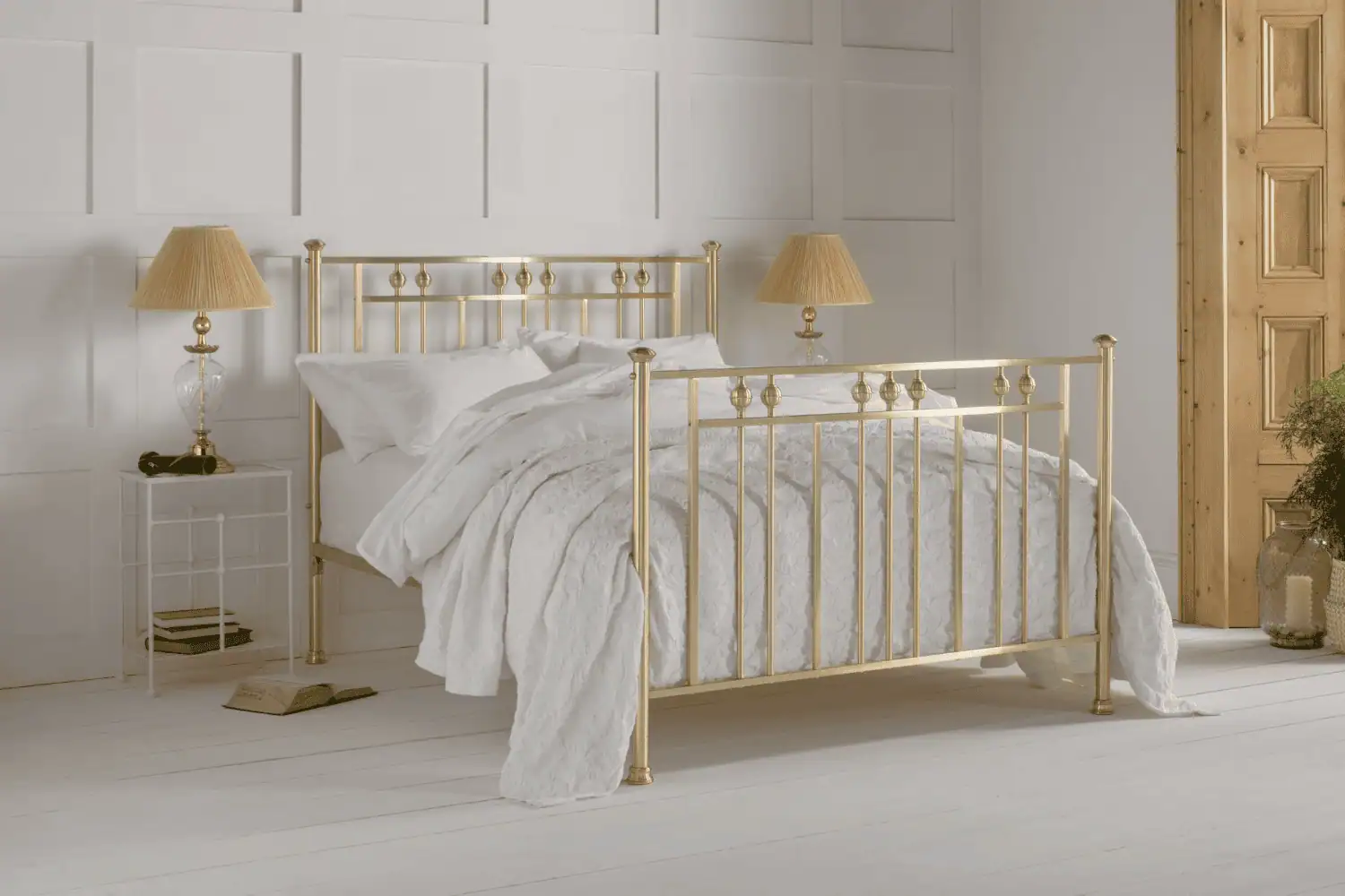 Rosie brass bed with round finials and soft gold finish, styled with white bedding in a serene bedroom