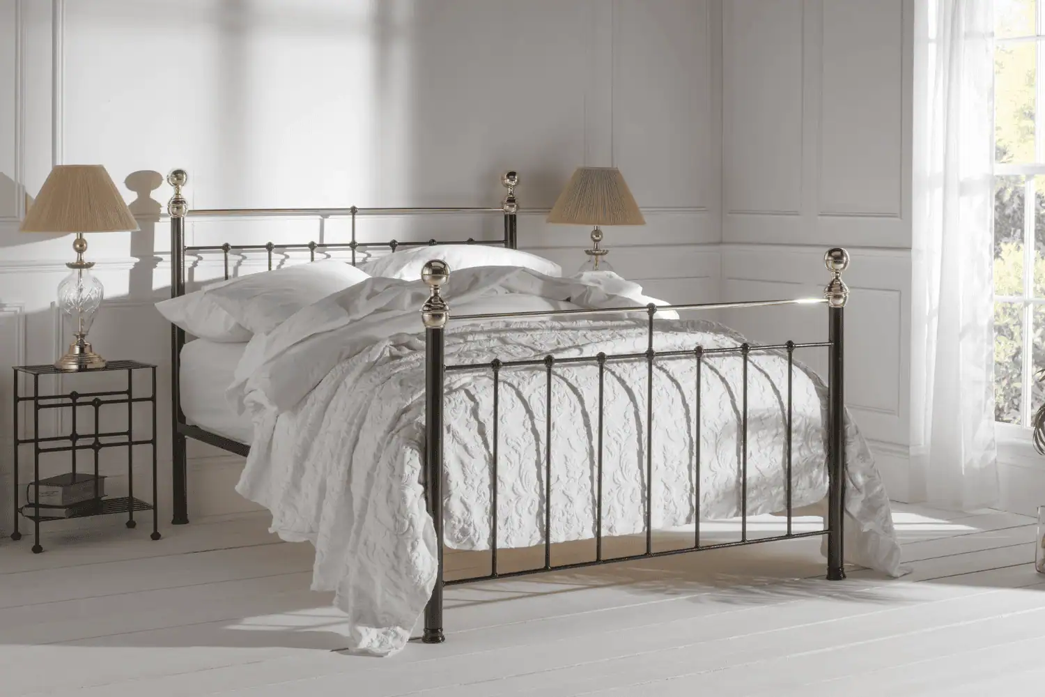 Albert bed frame with black iron structure and brass finials, styled in a white minimalist bedroom