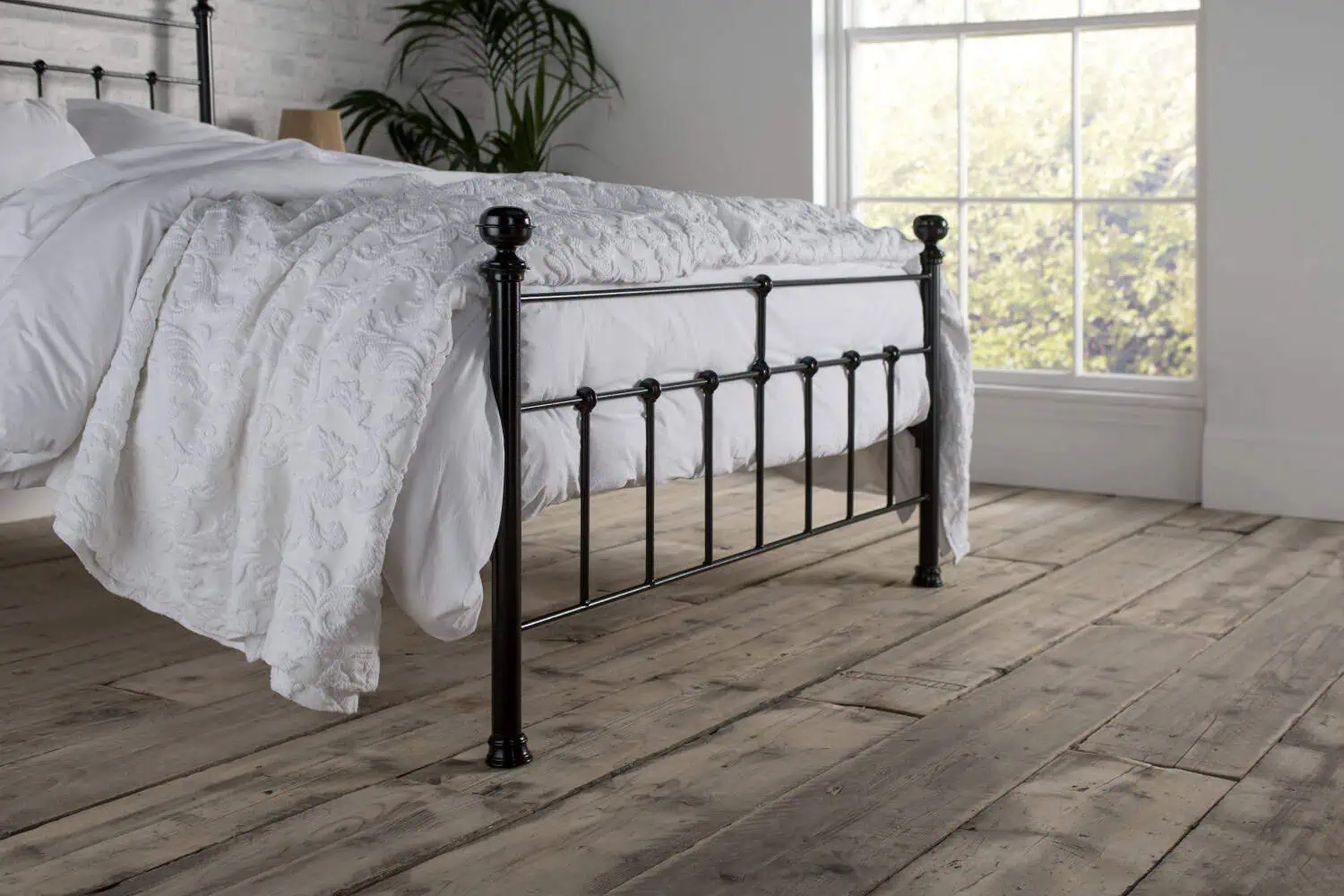 Angled view of the Sophie iron bed frame with curved footboard and elegant turned posts
