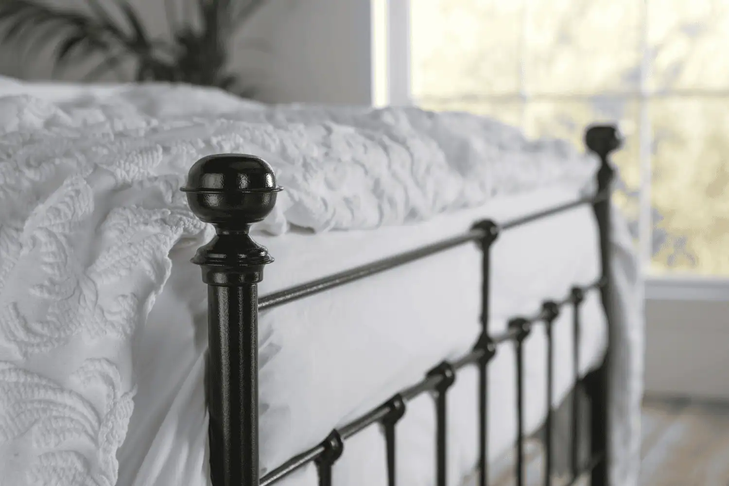 Close-up of Sophie bed’s curved rail and detailed round finial with black iron finish