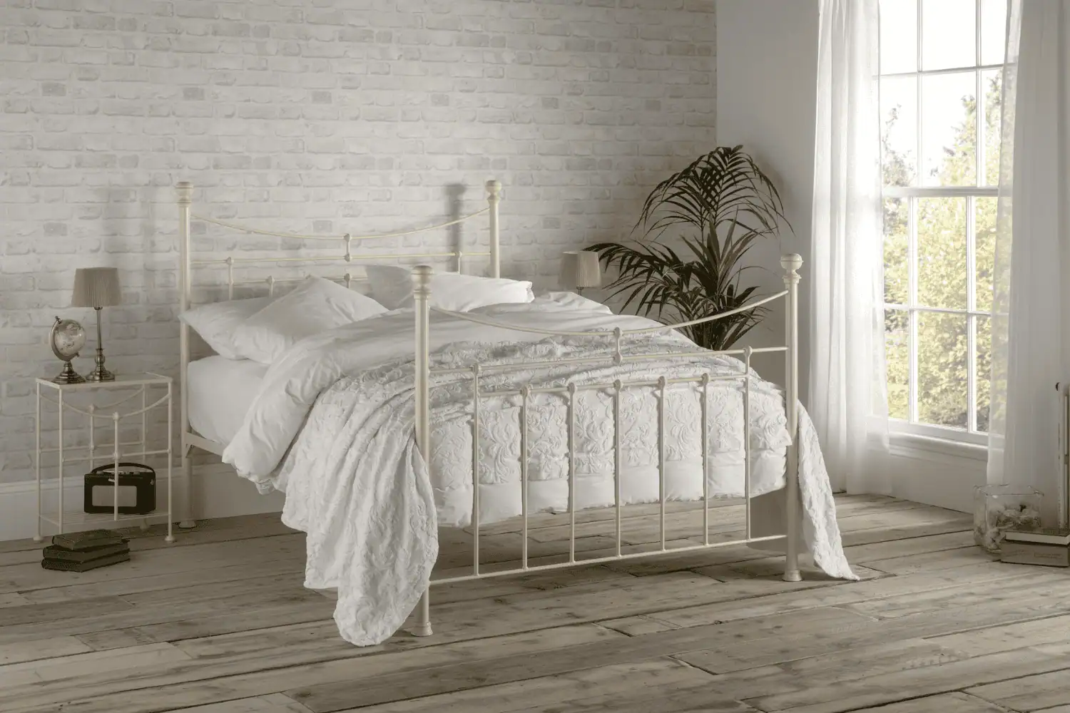 Lily iron bed frame in soft cream finish with curved headboard and footboard, styled in a cosy neutral bedroom