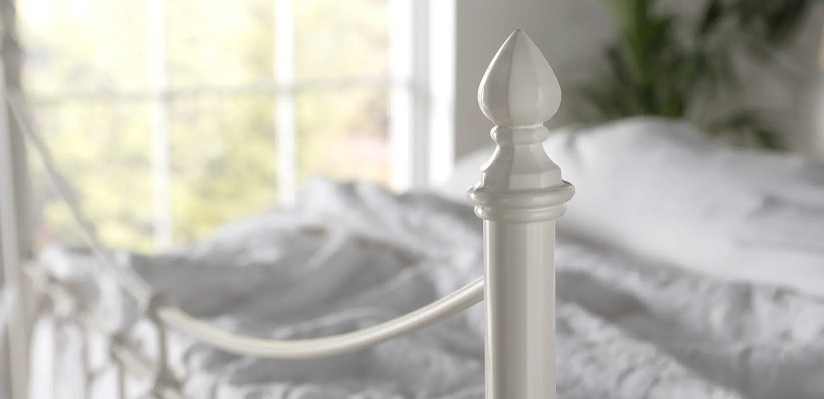 Close-up of Emily iron bed’s finial in ivory finish, featuring a smooth, decorative rounded top