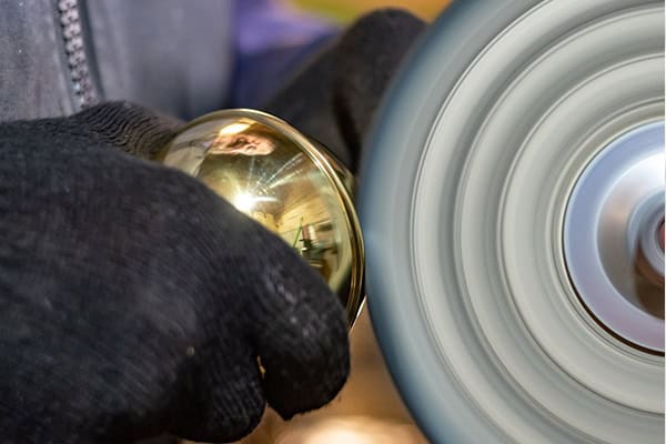 Brass detailing – the final touch on our handmade bed frames Craftsman polishing a brass finial to finish a handmade bed