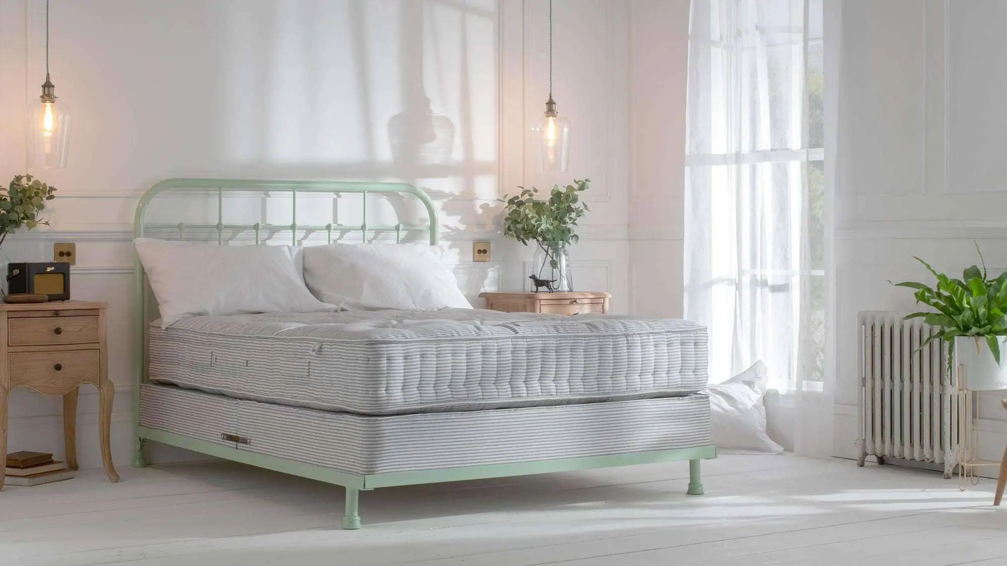Handmade iron bed with upholstered headboard and natural fibre pocket spring mattress in a light-filled bedroom