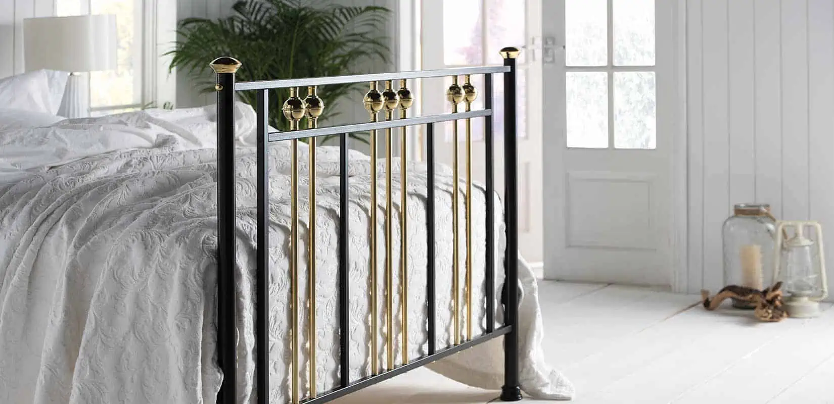 Side angle of Dolly bed showcasing polished brass finials and vertical rail design