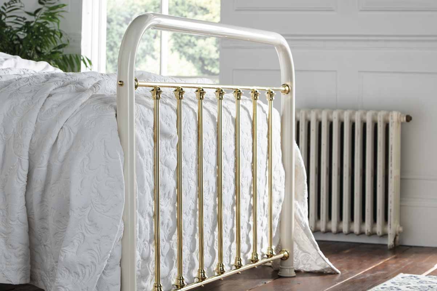 Angled side view of William brass bed showing its glossy brass finish and arched headboard design