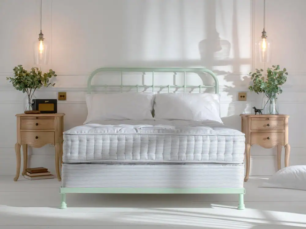 natural fibre british made wool mattress sitting on a sprung divan base, featuring a mint green dormatory style iron bed headboard