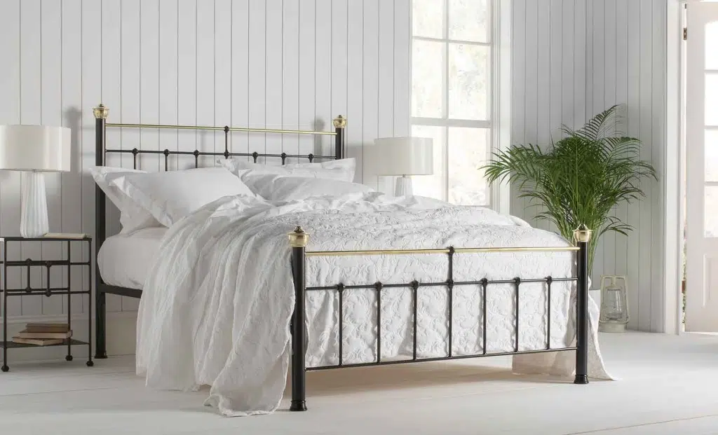 king size metal bedframe with brass detailing dressed with white bedding - with a low footboard it is great for small bedrooms