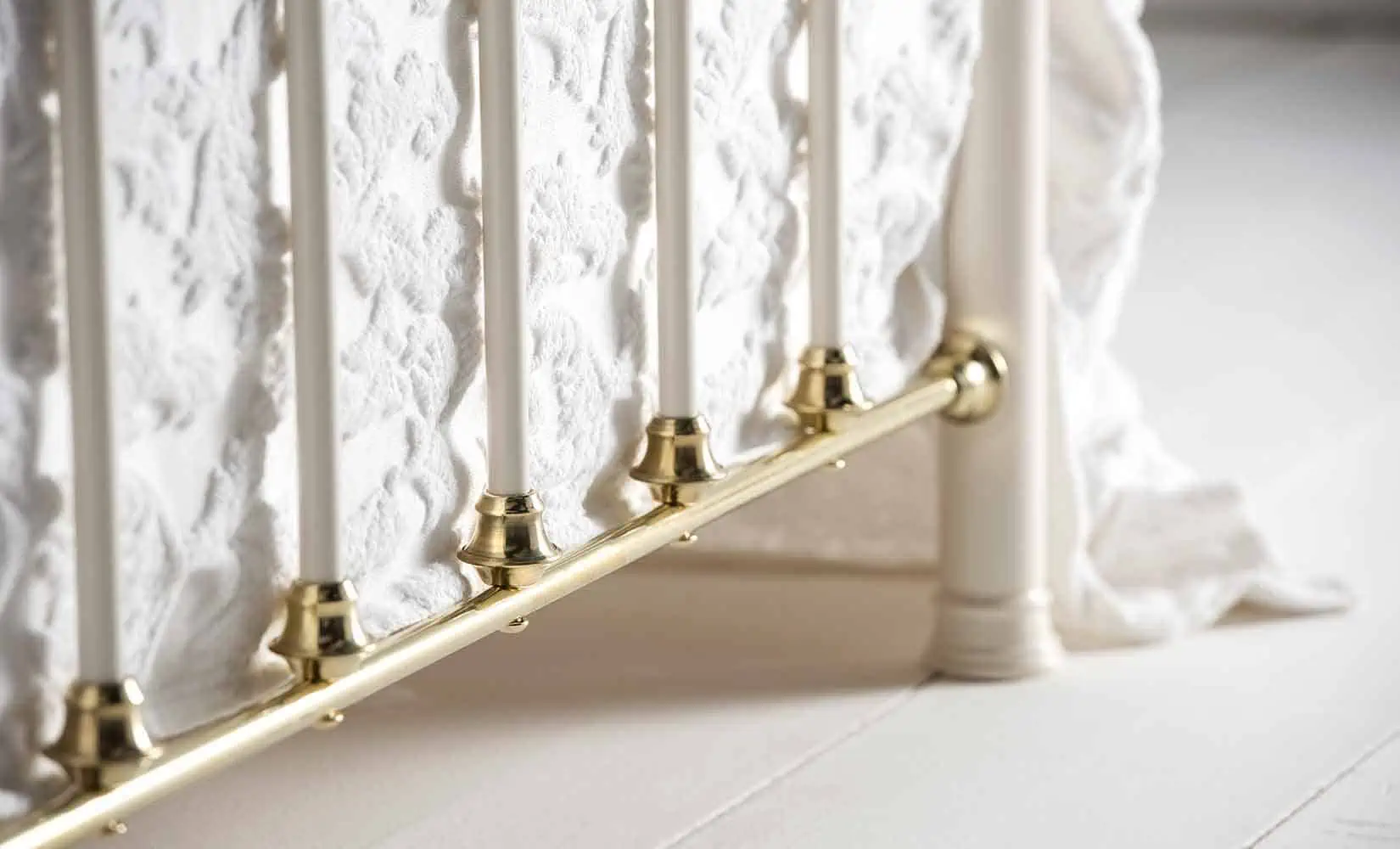 Close-up of Lottie bed's brass detailing along the bottom rail and vertical rods