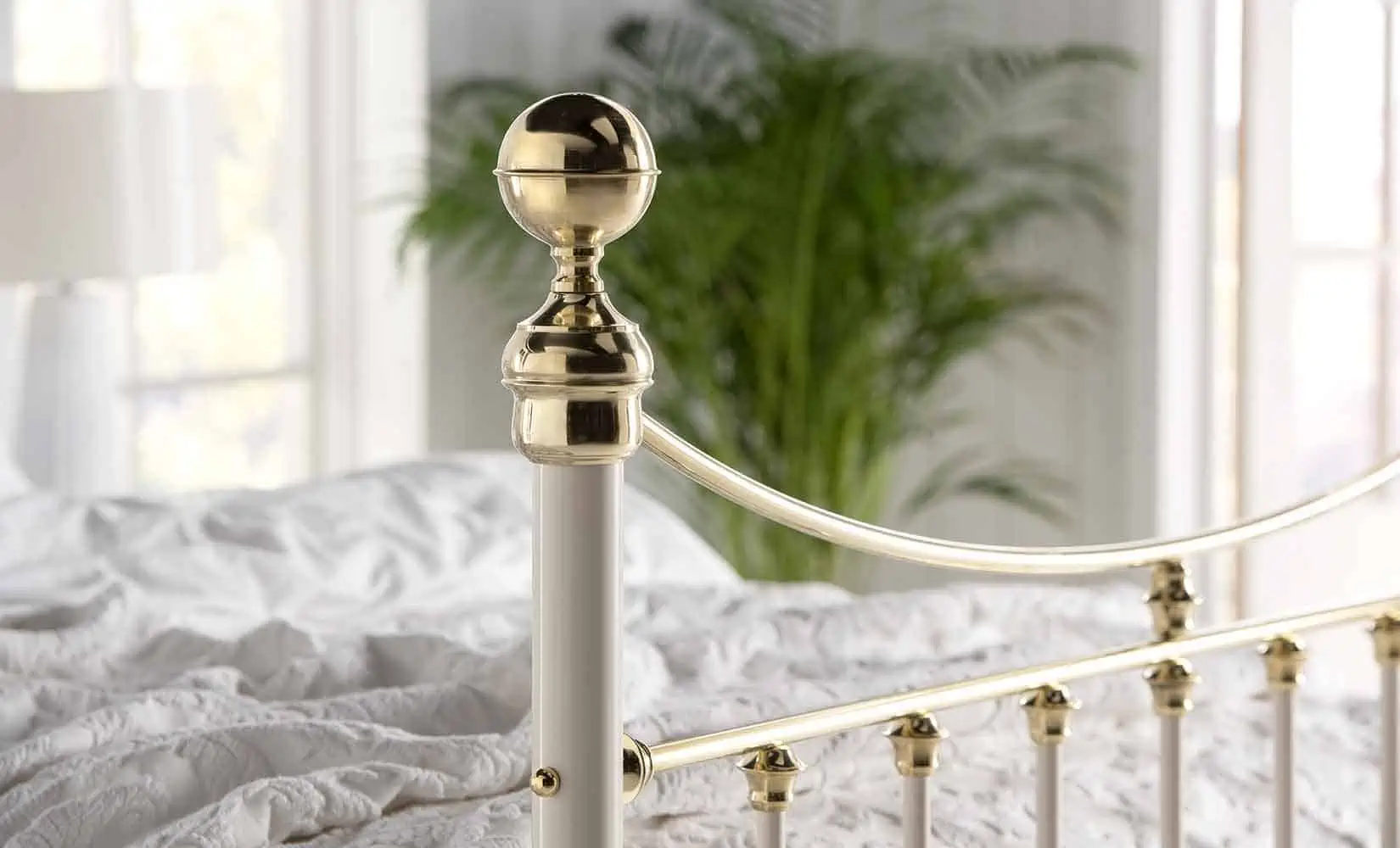 Finial close-up of the Lottie bed showing glossy brass top and cream metalwork