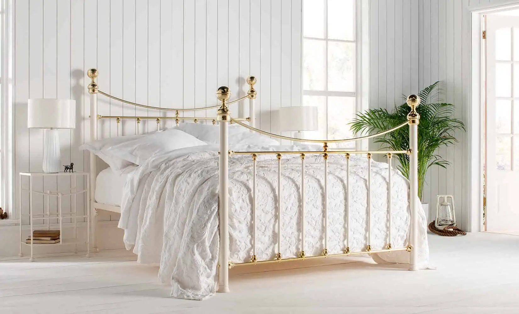 Lottie brass bed with curved headboard and white bedding in a light-filled classic bedroom