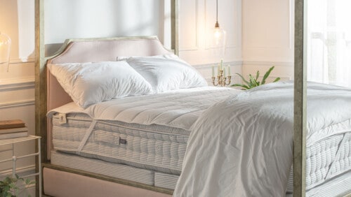 wool mattress protector pictured on four poster iron bed