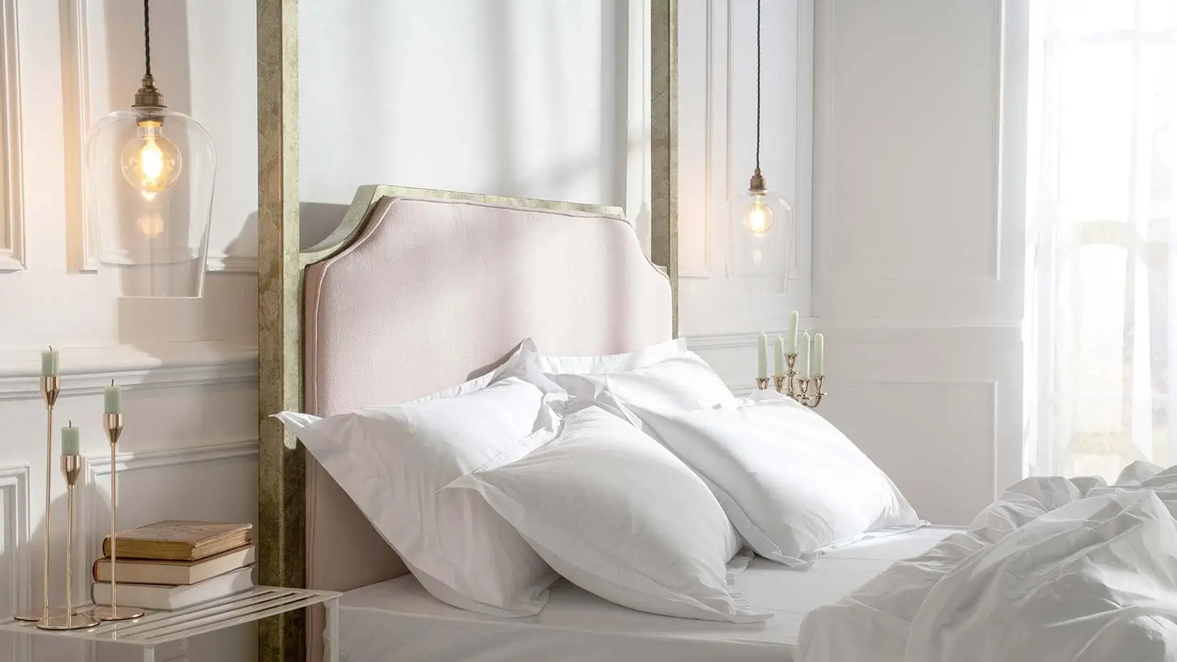Aurora four-poster bed with statement blush pink upholstered headboard framed by gold-finished posts