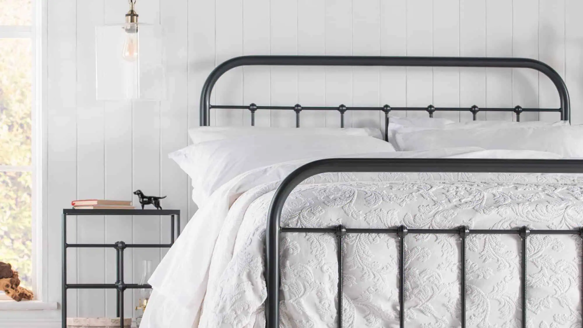 Side angle of the Archie iron bed showcasing curved iron details and elegant finish.