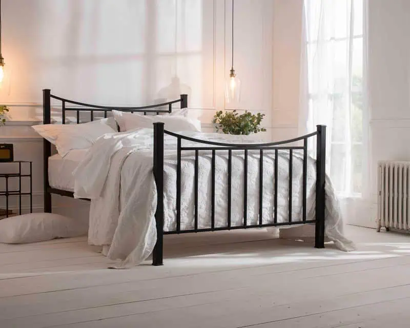 morder handcrafted iron bed powder coated in black dressed in cotton bedding