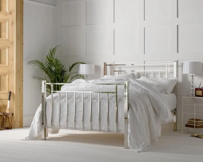 geometric inspired art deco inspired nickel bed with a high polished finishes dressed in white bed linen