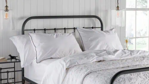 white cotton washable pillow covers displayed on a dark grey dormitory style iron bed frame, accompanied by white bedlinen.