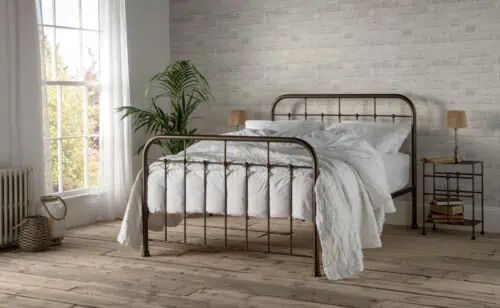 A handcrafted wrought iron bed frame with FSC-certified Scandinavian wood slats, styled in a bright bedroom with rustic flooring and soft white bedding.