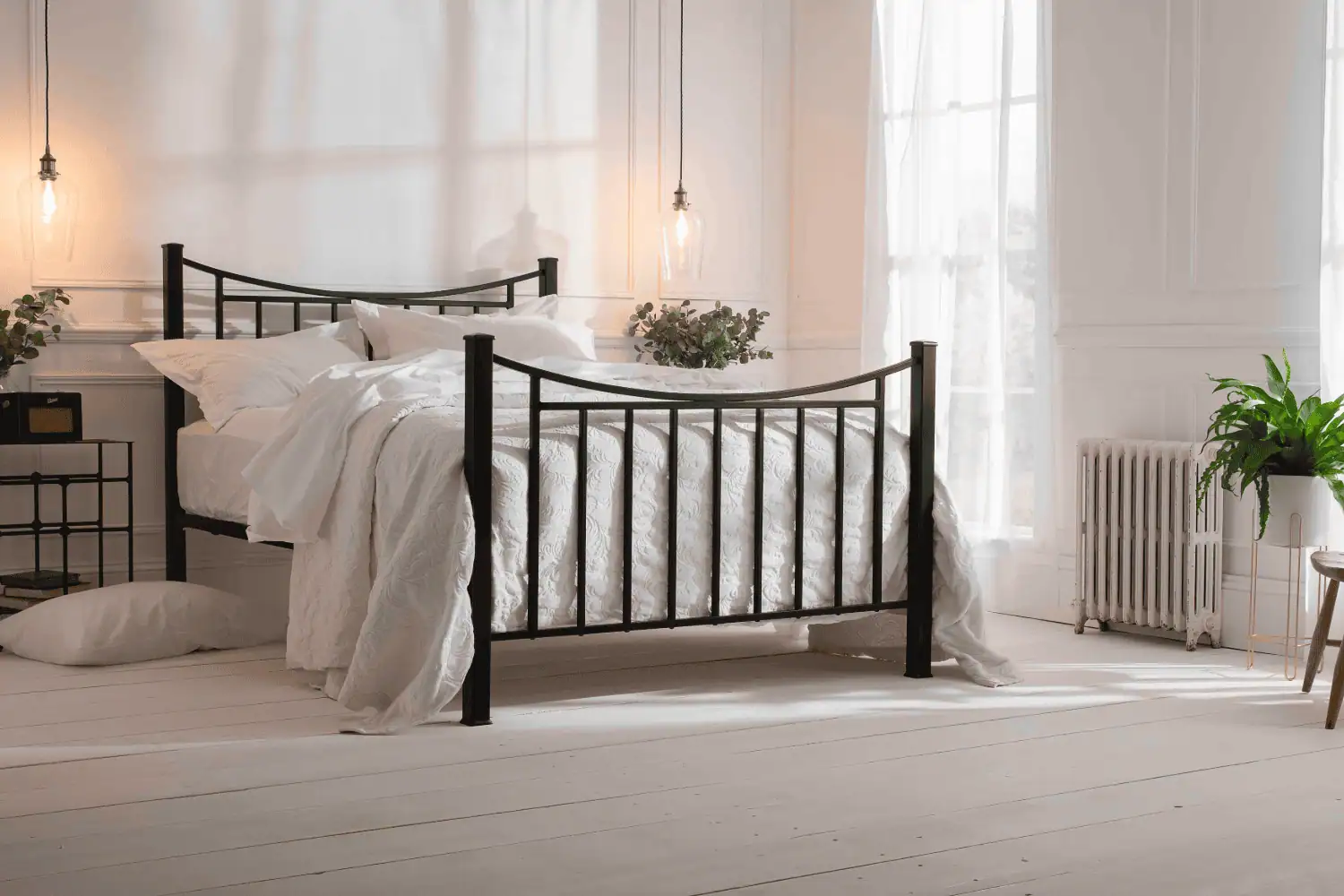 Black iron bed with curved headboard and soft white bedding in a cozy room