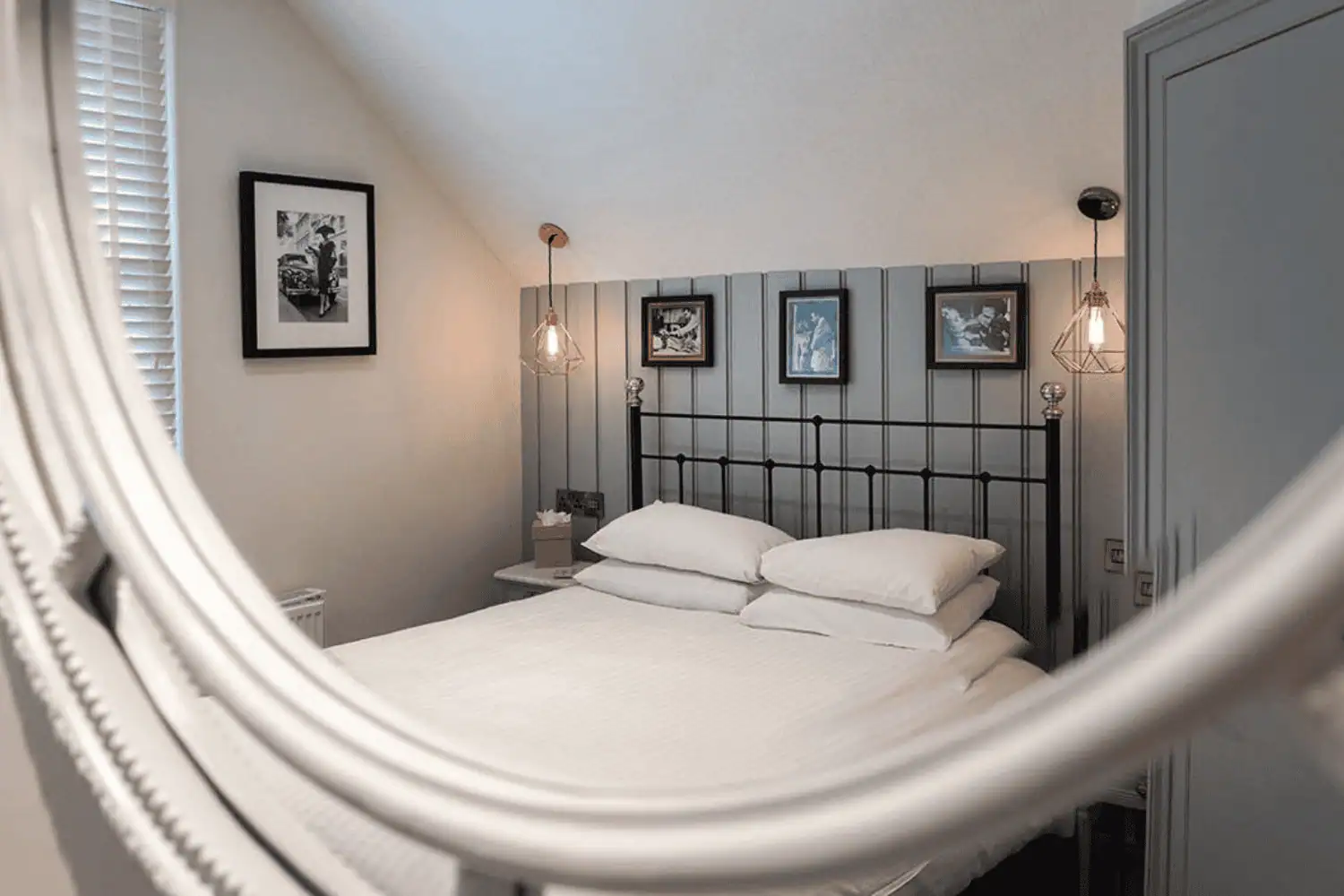 Handmade wrought iron bed photographed through mirror detail in a cosy bedroom