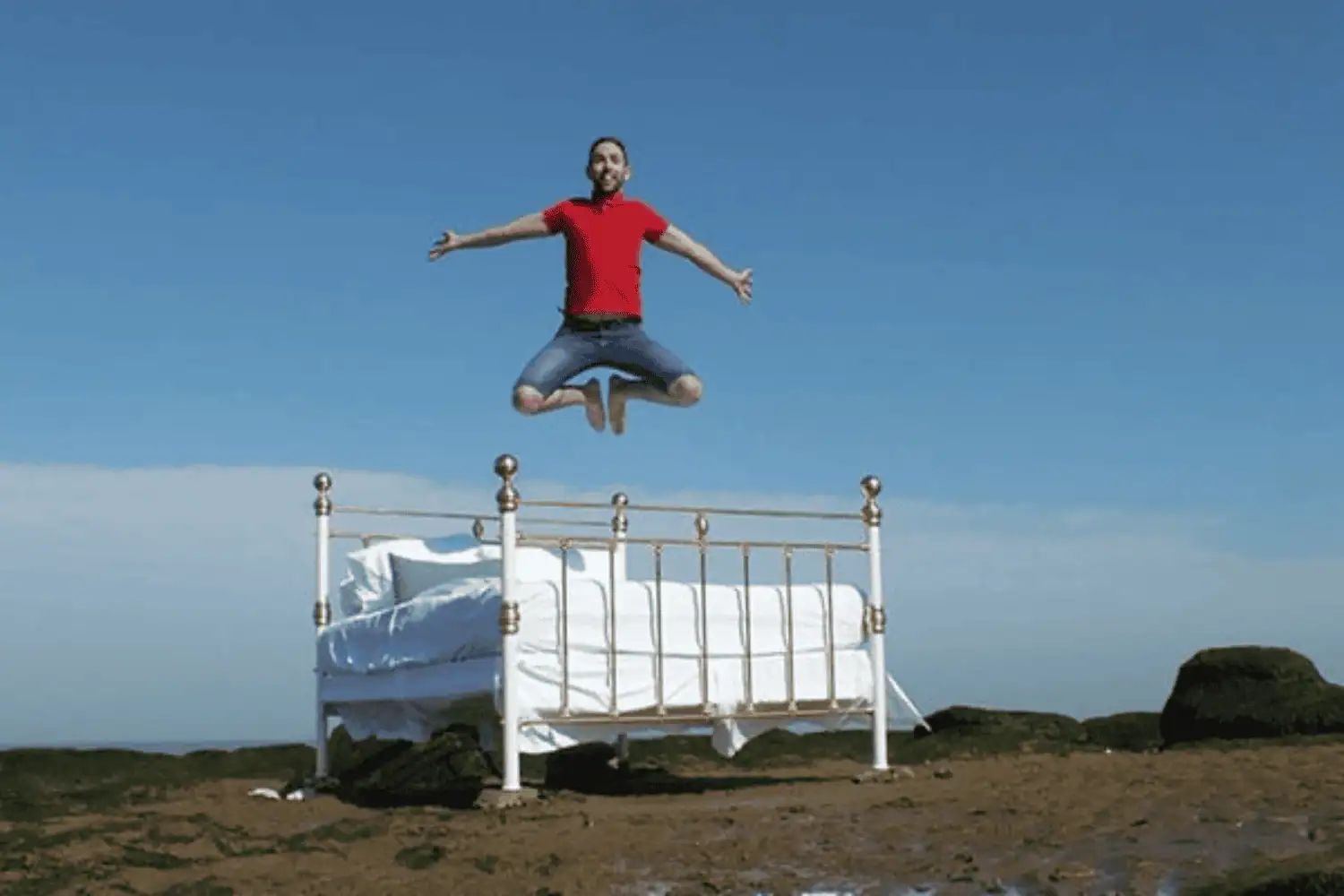 Man jumping with joy on a handmade wrought iron bed outside, highlighting durability and strength