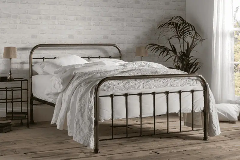 Edward Bed The Edward traditional iron bed with curved headboard and clean cast feet, shown in a heritage-inspired bedroom