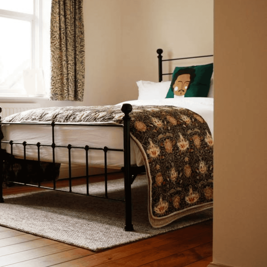 A black iron bed frame dressed with dark checkered bedding in a modern, minimalist bedroom.