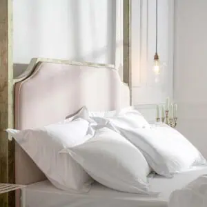 Elegant wrought iron and brass bed with white bedding in a bright bedroom.