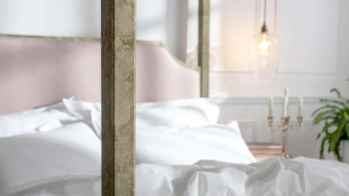 Elegant wrought iron and brass bed with white bedding in stylish bedroom.