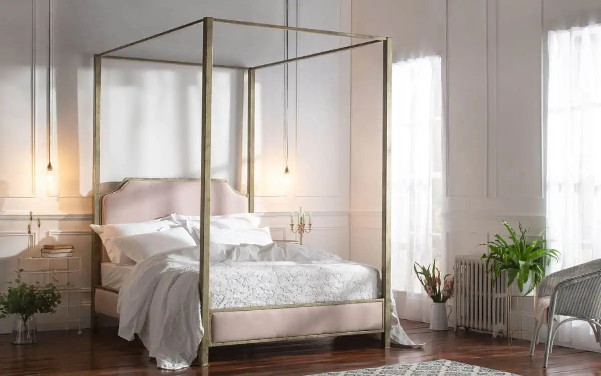 Luxurious wrought iron and brass bed in a bright bedroom setting.