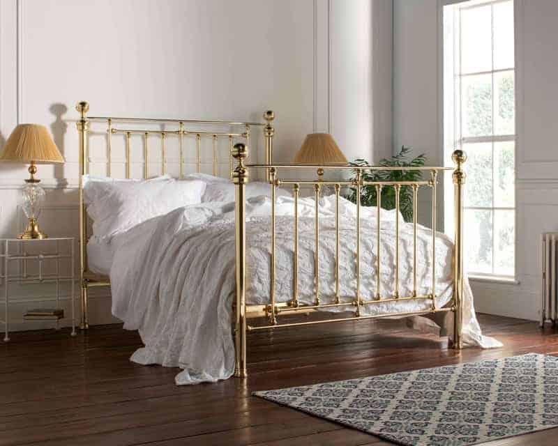 Elegant brass and wrought iron bed in a bright bedroom setting.