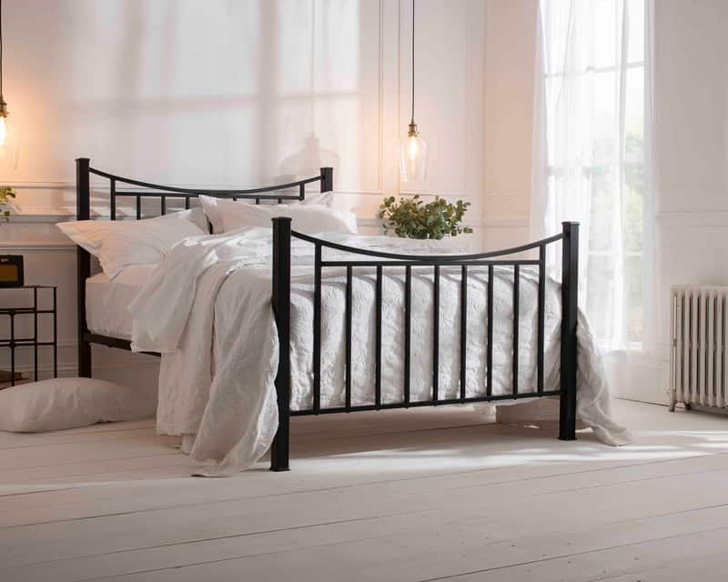Elegant iron and brass bed in a bright bedroom setting.