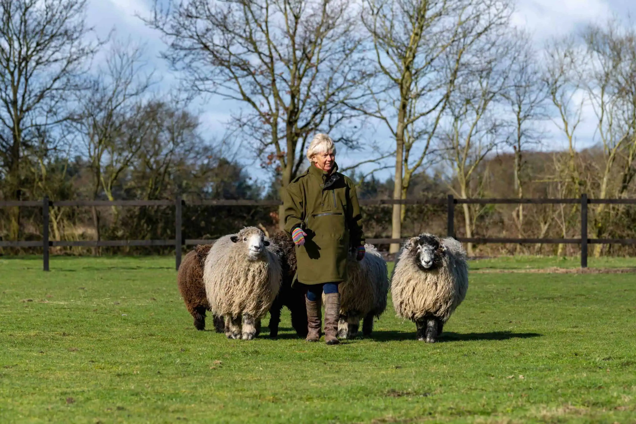 Amanda Oldfield, founder of Iron & Brass Bed Company, standing with her sheep in a grassy field